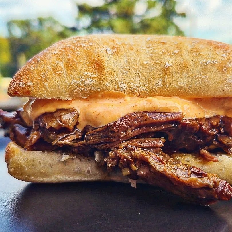 Sweet and savory ginger garlic beef sandwich on a ciabatta roll with sriracha mayo